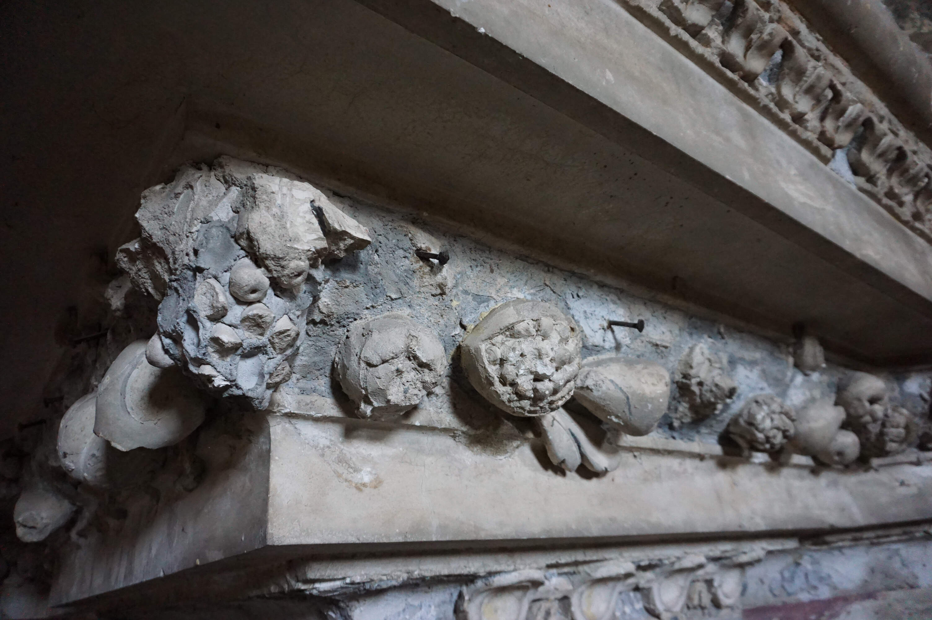 Detail of a deteriorated stucco decoration, showing exposed supporting nails that are usually hidden.
